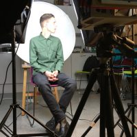 Collodion photography: Here's a subject, under bright lights, surrounded by some of the necessary paraphernalia