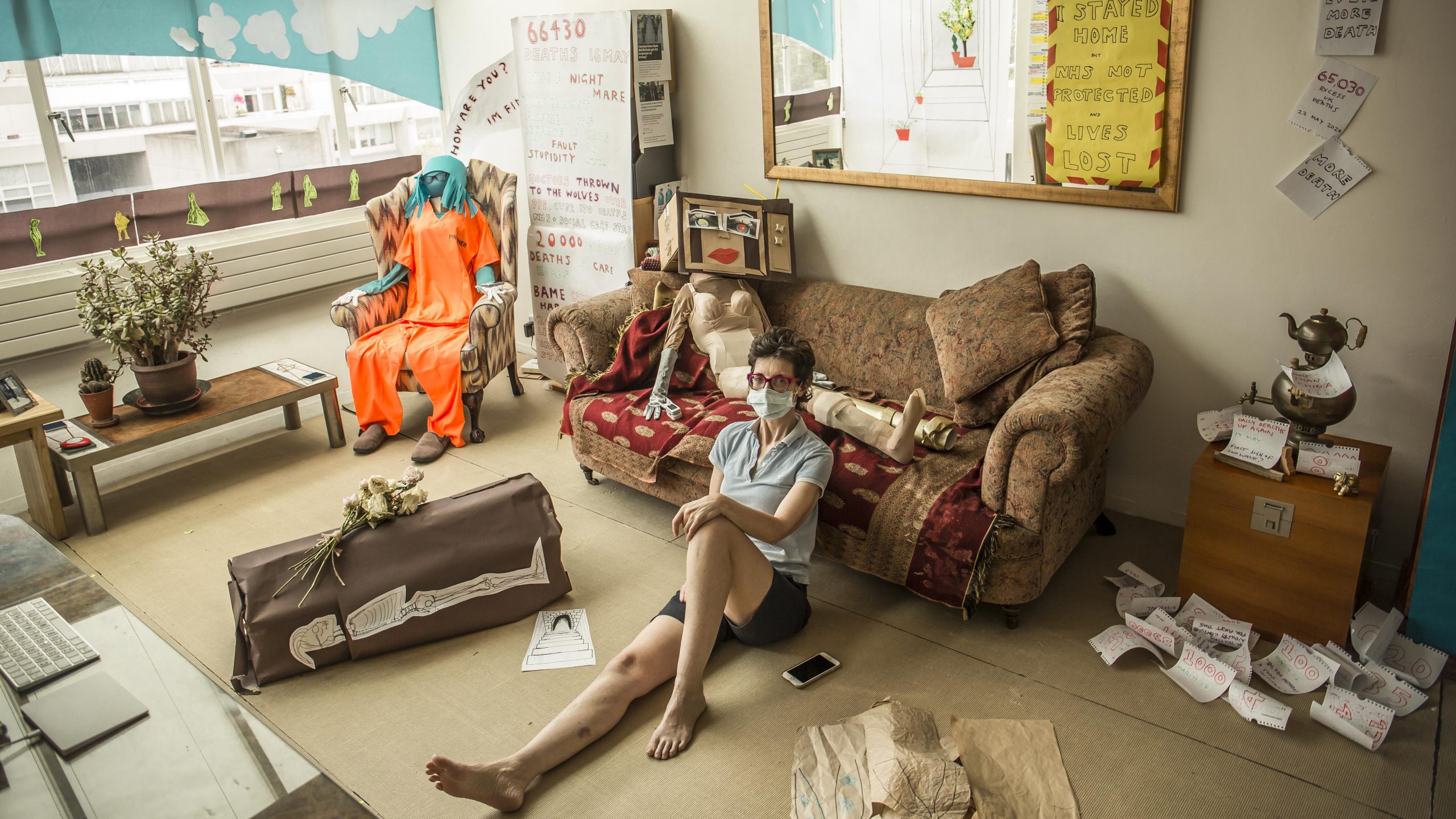 Im sitting - in my shorts - in my installation. Theres a prisoner in Guantanamo orange ranting on her phone, a coffin with the corpse shown rotting on the side, and a vulnerable naked woman lying on the sofa. Theres lots more not visible here.