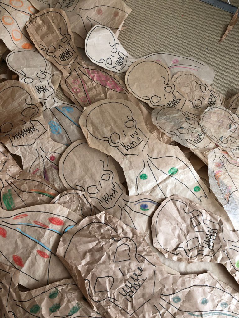 Dead bodies ankle deep on the floor. Skulls and abnormal Xrays - drawn on recycled packsging
