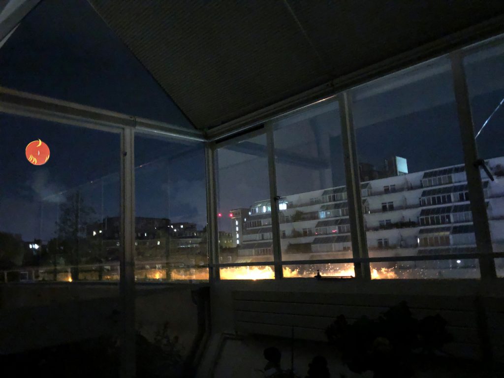This is a night time view form inside my front room. You can get an idea of the extent of my windows. And see the flats opposite me. THeres an orange moon with crescent moonlets high up in the far left of the windows. 