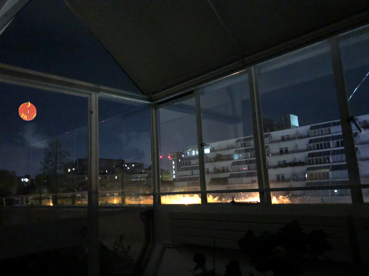 This is a night time view form inside my front room. You can get an idea of the extent of my windows. And see the flats opposite me. THeres an orange moon with crescent moonlets high up in the far left of the windows.